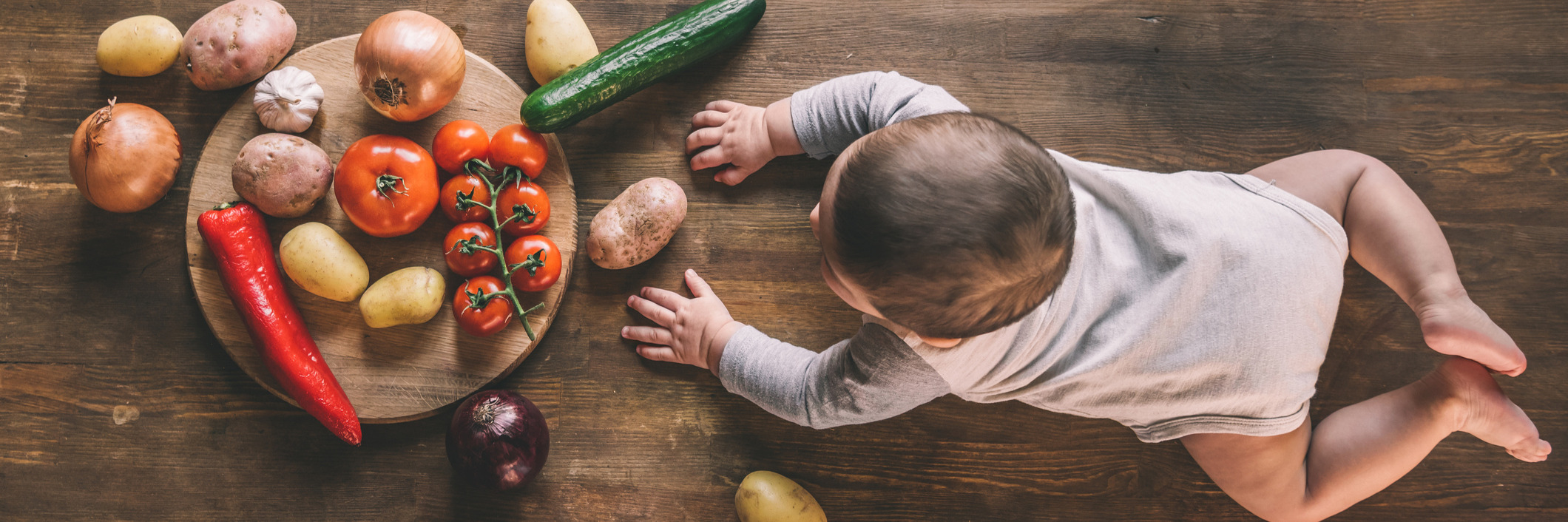 Bébé qui rampe devant un étalage de légumes