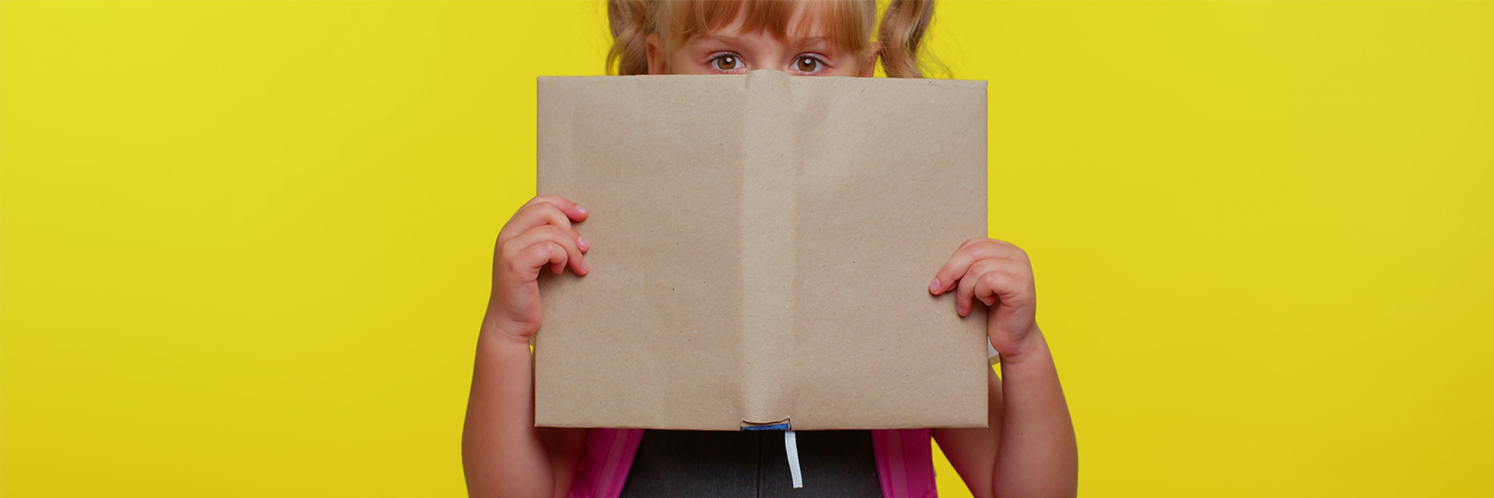 Enfant pris sur le fait qui se cache derrière un livre