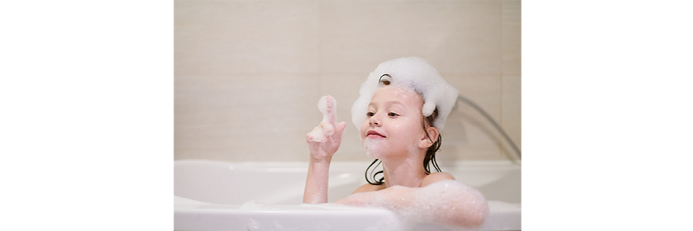 petite fille qui joue avec de la mousse dans son bain 